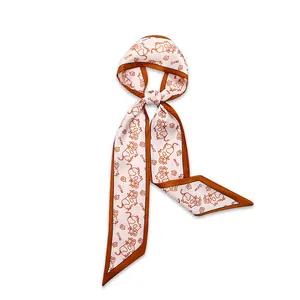 Detail view of narrow silk scarf featuring bright orange borders and cute cartoon cow pattern
