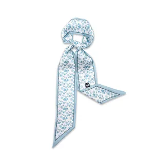 Elegant light blue skinny silk scarf with floral pattern tied in a soft decorative knot