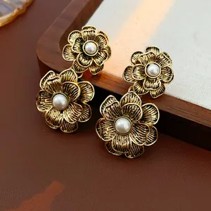 Detailed macro view of vintage gold-tone floral earrings with elegant pearl centers