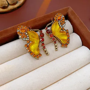 Close-up of vintage butterfly earrings with amber rhinestones in a brown jewelry box