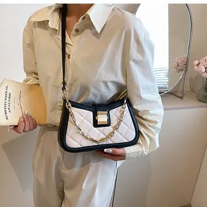 Quilted black and white crossbody bag with gold chain and metal lock on a model