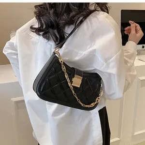 Close-up of a stylish black quilted shoulder bag with a gold chain and clasp detail