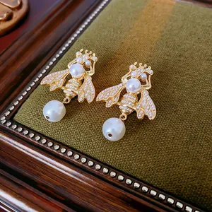 Detailed macro close-up of vintage palace style gold bee earrings with pearls and crystals