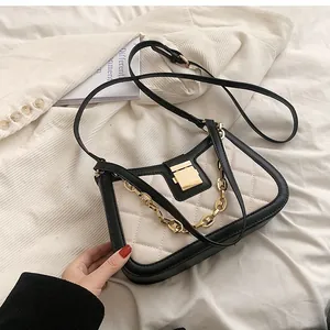 Detailed shot of a trendy quilted black and cream crossbody bag with gold chain