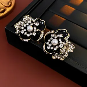 Detail of vintage flower stud earrings with black enamel and white rhinestones
