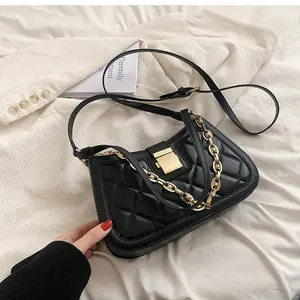 Close-up of black quilted shoulder bag with gold chain and metal clasp detail