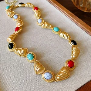 Detail shot of vintage style matte gold necklace with colorful stones on linen background