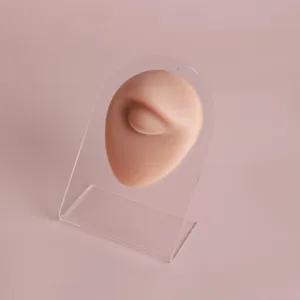 Close-up of a realistic silicone eye piercing practice model on a clear acrylic stand