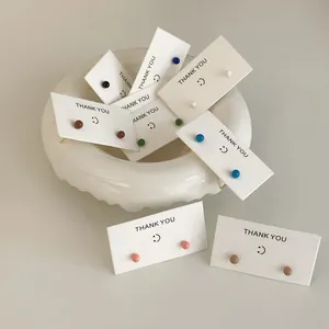 Vibrant mini candy-colored stud earrings set on white cards with cute smiley faces
