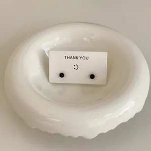 Close-up of minimalist black mini bean stud earrings on a white Thank You display card