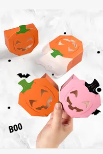 Detail view of hollow Halloween pumpkin candy boxes in orange and pink being held
