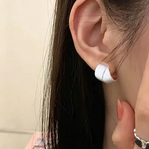 Niche designer matte white sculptural earring worn on an Asian female model's ear