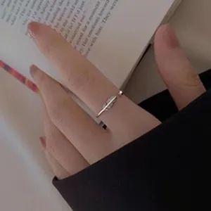 Close-up view of a minimalist S925 sterling silver feather open ring on a finger.
