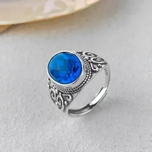 Detailed macro view of an ornate S925 silver ring featuring a faceted oval blue gemstone