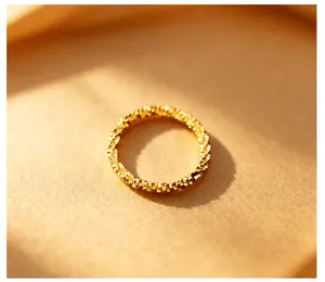 Macro shot of a shimmering gold textured ring on a warm paper background.