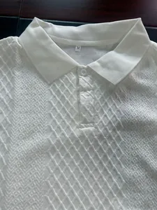 Close-up detail of white men's polo shirt featuring an intricate jacquard diamond texture