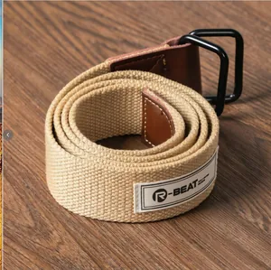 Close-up of khaki canvas belt with black double D-ring buckle on wood background