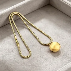 Detailed view of a golden titanium steel snake chain necklace with a large smooth sphere