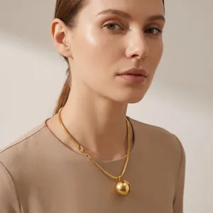 Detail view of a gold titanium steel snake chain necklace with large ball pendant.
