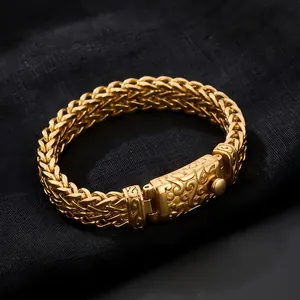 Detailed view of the ornate engraved clasp on a gold-toned men's wheat chain bracelet.