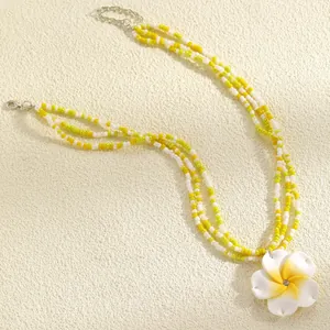 Detailed view of a multi-strand beaded necklace with a yellow Frangipani flower