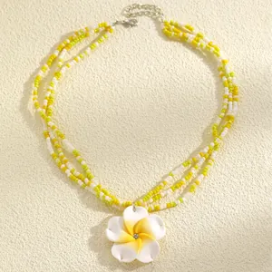 Detailed view of three-strand beaded necklace with frangipani flower pendant detail