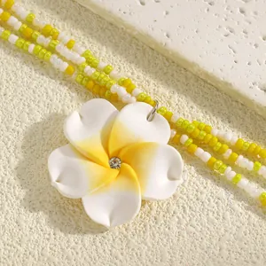 Detailed view of white and yellow frangipani flower necklace with multi-strand beads
