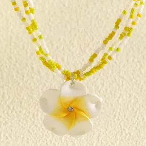 Detailed view of a sweet dopamine style plumeria flower pendant necklace with seed beads.