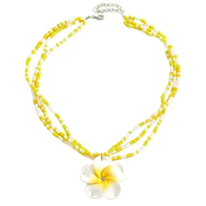 Detail of multi-strand beaded necklace with yellow and white frangipani flower pendant