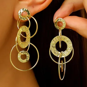 Vue détaillée des boucles d'oreilles créoles dorées irrégulières martelées texturées.