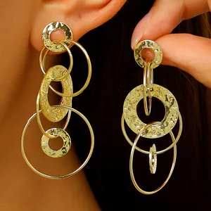 Détail de boucles d'oreilles dorées géométriques avec disques martelés et anneaux