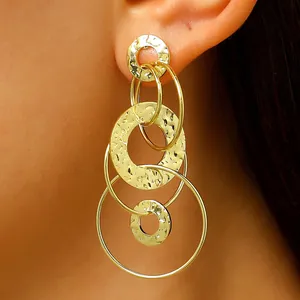 Vue détaillée des boucles d'oreilles créoles dorées avec texture martelée et fini.