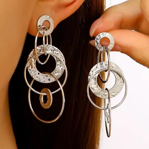 Gros plan de boucles d'oreilles multi-anneaux argentées martelées sur une oreille.