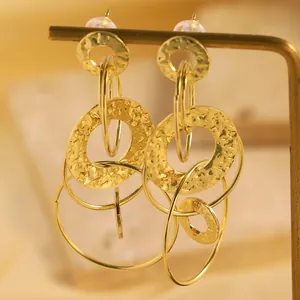 Gros plan de boucles d'oreilles dorées géométriques avec texture martelée unique.