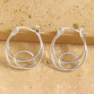 Gros plan de boucles d'oreilles créoles triples géométriques en argent minimalistes.