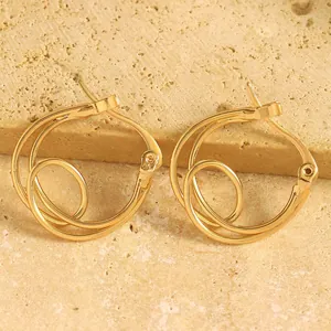 Gros plan de boucles d'oreilles créoles dorées géométriques au design tourbillonnant