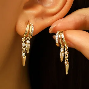 Elegant gold hoop earrings with zircon studded spike tassels worn on ear