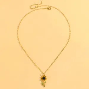 Vue macro détaillée d'un collier avec pendentif tournesol doré et accents de feuilles.