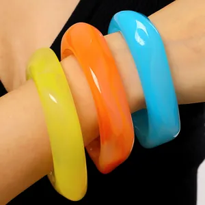 Nahaufnahme von drei bunten, groben geometrischen Resin-Armreifen in Gelb Orange Blau