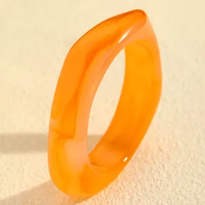 Detaillierte Ansicht eines klobigen orangefarbenen Harzarmreifs mit Marmoreffekt