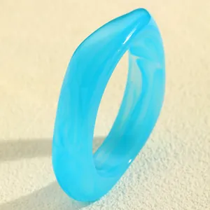 Nahaufnahme eines blau marmorierten Harz-Armreifs mit unregelmäßigem geometrischem Design