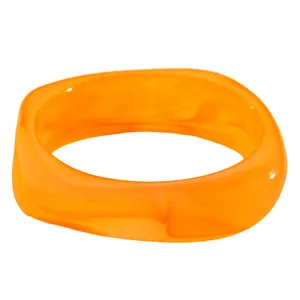 Detailansicht eines klobigen orangefarbenen Harzarmbands mit marmoriertem Wirbelmuster.