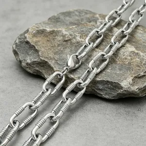 Macro detail of a 10mm stainless steel cable chain with textured links on a stone.