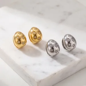 Detailed close-up of gold and silver teardrop earrings with sparkling star engravings.