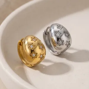 Detailed macro view of gold and silver drop earrings with engraved stars and crystals