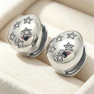 Macro view of silver waterdrop earrings featuring star engravings and tiny crystals