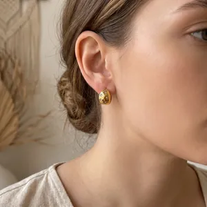 Close-up of 18K gold plated stainless steel star earrings with diamond inlay on ear