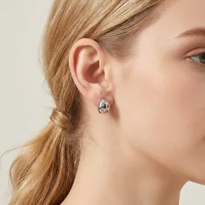 Close-up of star engraved silver water-drop earring worn by a model