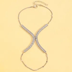 Detailed view of a silver-tone alloy hand chain with rhinestone X-motif on yellow