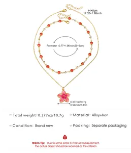 Detail view of double layer gold necklace with pink flower pendant and red crystals